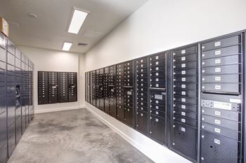 A row of black mailboxes are lined up against a wall.